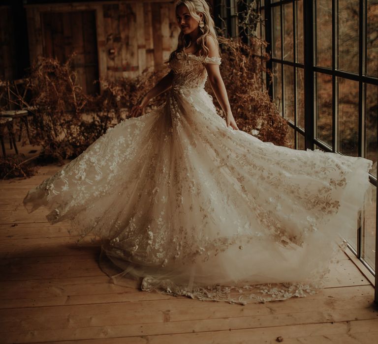 Bride in an off the shoulder appliqué wedding dress twirling 