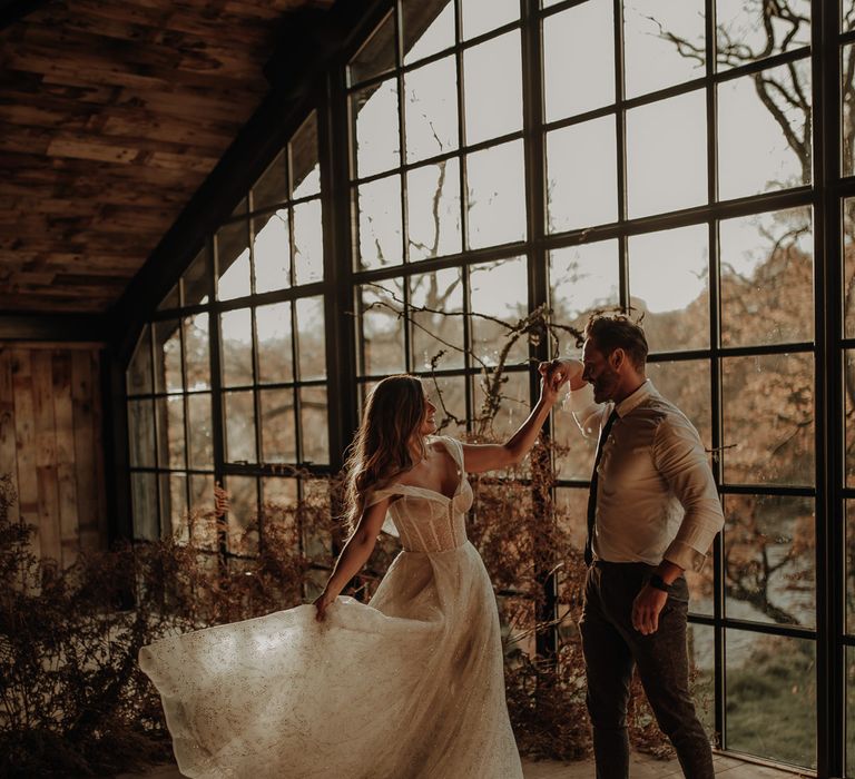 Groom in a shirt and tie twirling his bride in a lace wedding dress at Hidden River Cabins wedding venue 