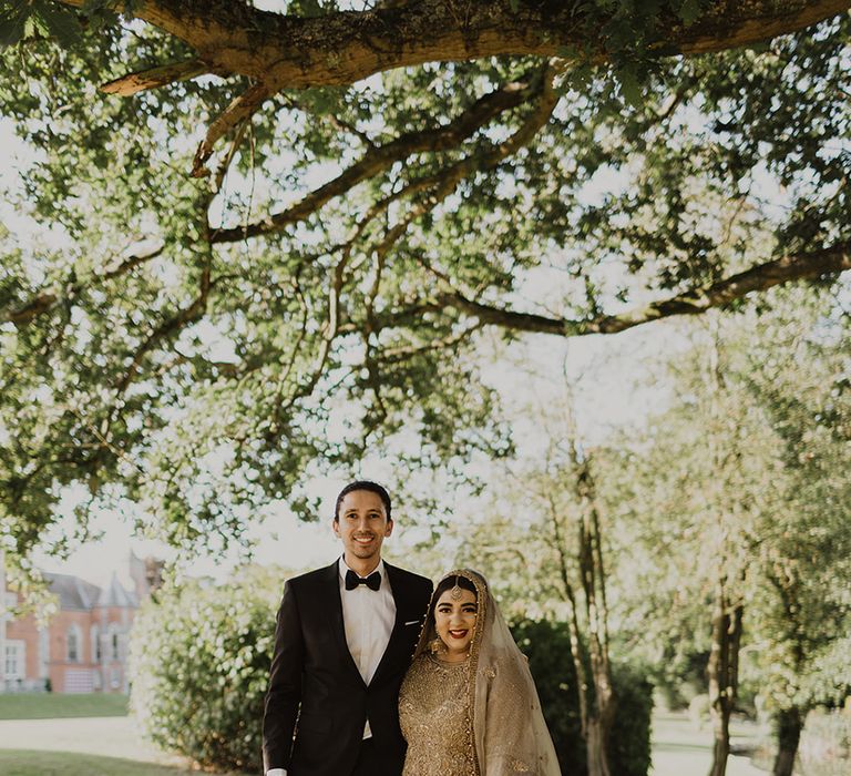 A bride and groom at after their Nikah ceremony. She wears an elaborate gold dress.