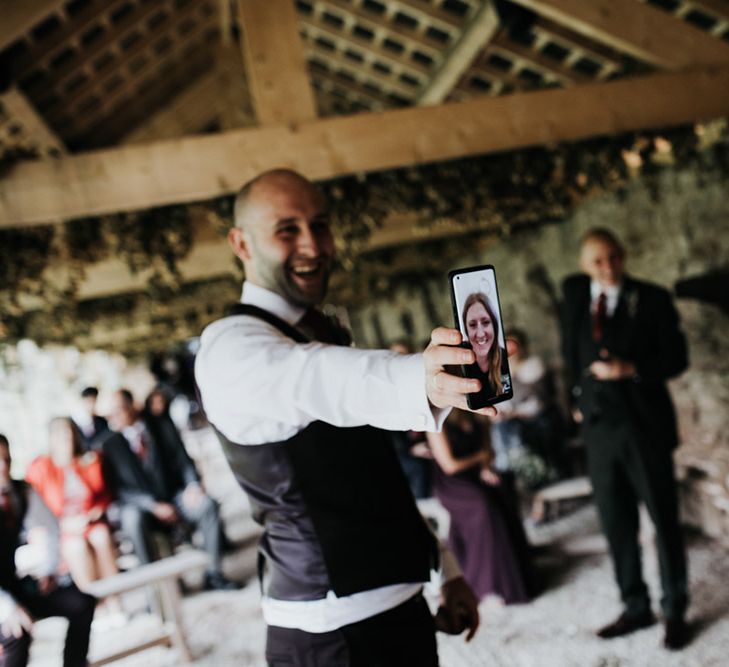 A wedding guest holds a phone up towards the bride and groom during a virtual wedding