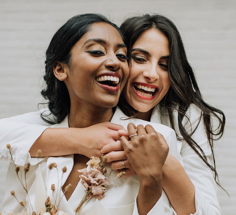 Two brides at all white wedding shoot with dried flowers and tailored bridal outfits