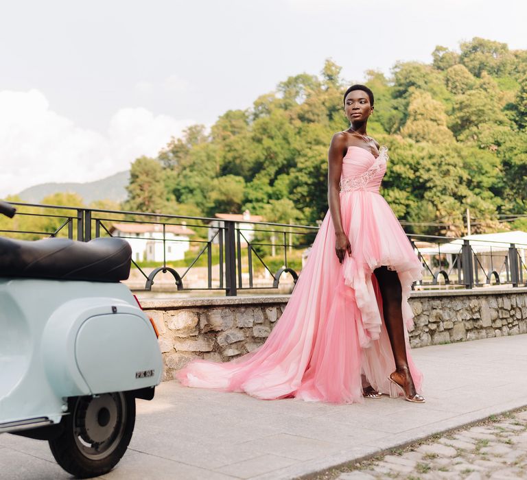 Bride wears pink bridal gown with sweetheart neckline and poses along bridge