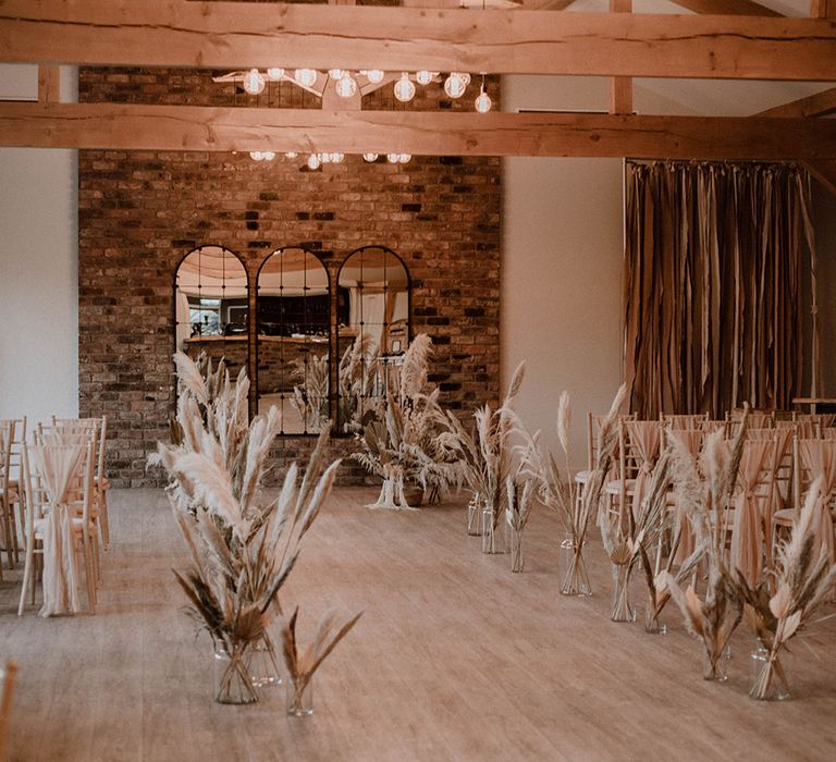 Pampas grass and palm leaves lining the aisle 