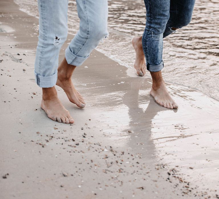 Grooms walk barefoot through the same wearing pale blue jeans rolled at the ankles