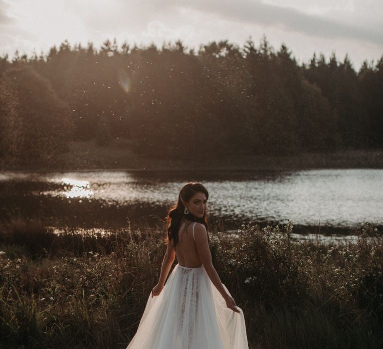 Bride wearing a layered tulle wedding dress at golden hour for moody romantic wedding shoot