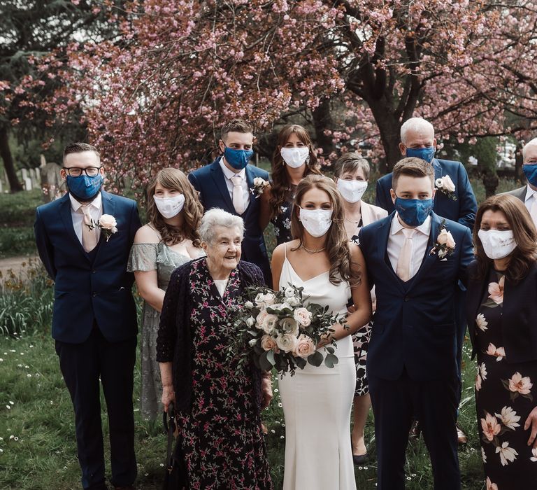 Bride and groom with their wedding party outside the church, everyone is wearing masks