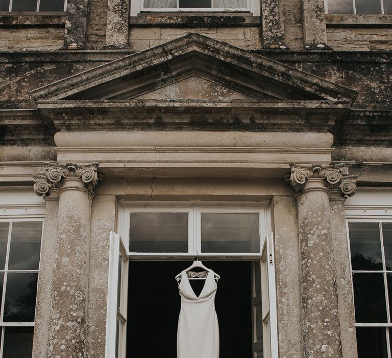 White Pronovias wedding dress with train hung up on a hanger in doorway at Came House Dorset