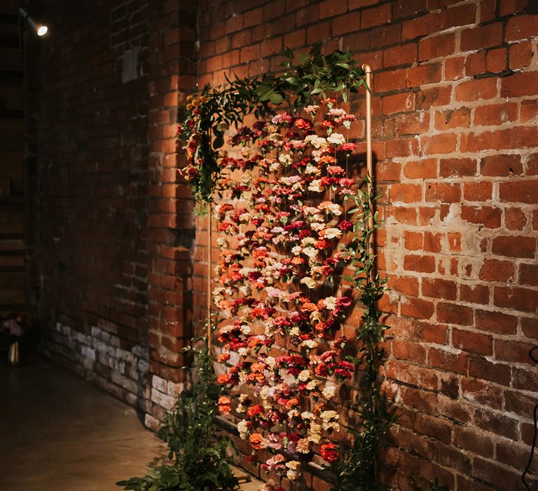 A floral installation makes the backdrop for a wedding ceremony.