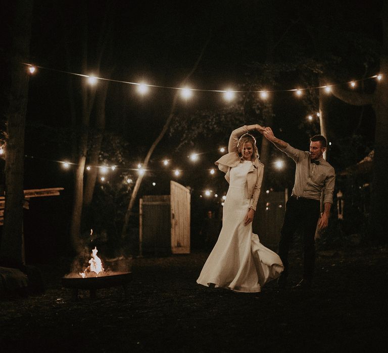 Groom twirls bride around outdoors on their wedding day