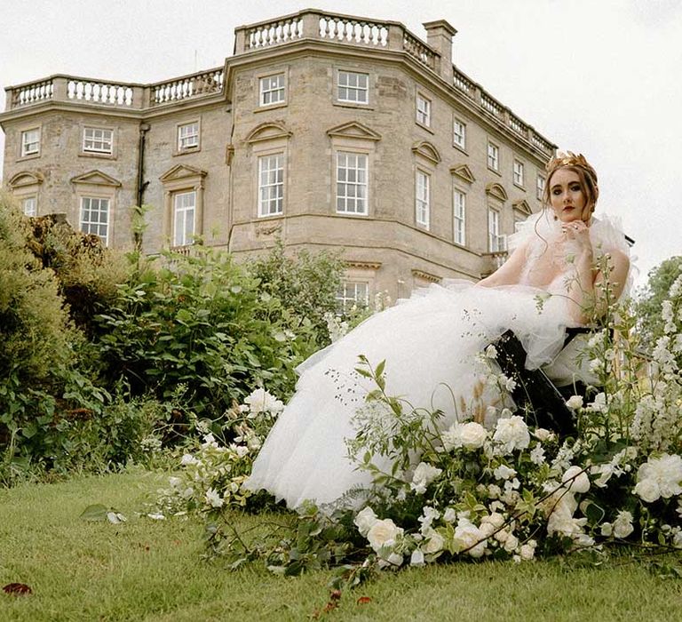 Bride in a wheelchair wearing a tulle wedding dress and gold headdress with white and green flowers decorating the wheels