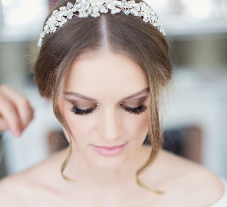 Bride in an off the shoulder dress with dark grey eye shadow and long lashes and barely there lipstick wedding makeup