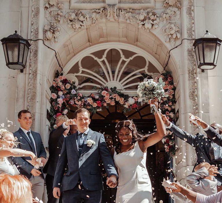 Bride & groom leave Chelsea Old Town Hall on their wedding day as guests throw colourful confetti around them