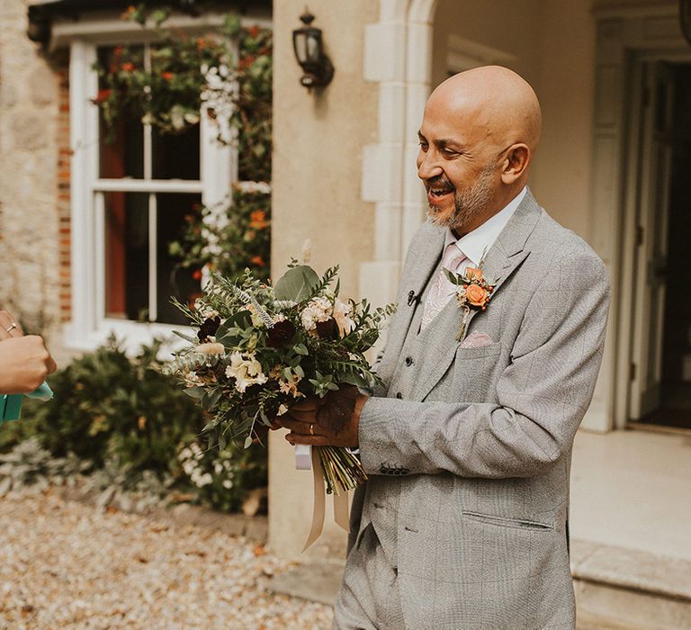 Wedding guest in grey suit with orange flower buttonhole 