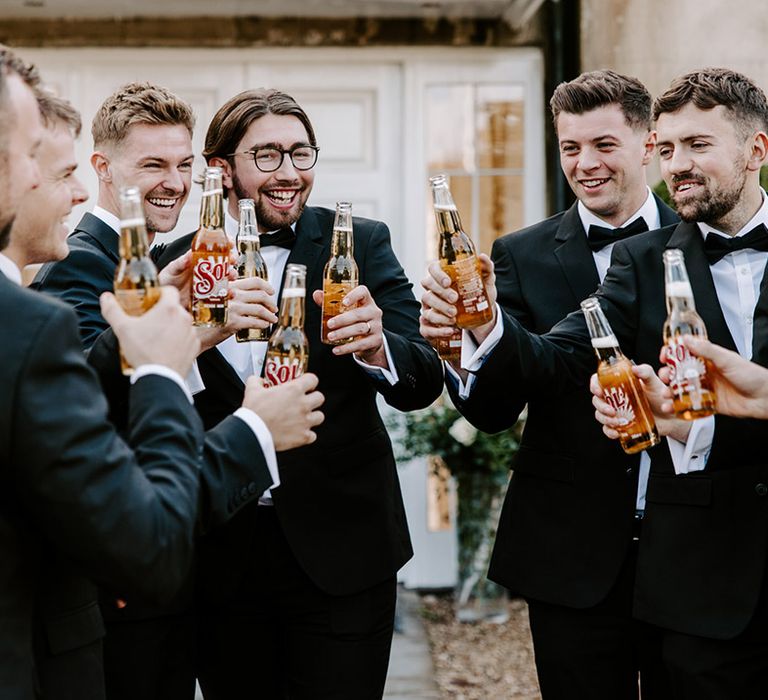 Groomsmen in tuxedos drinking beer on the wedding morning 