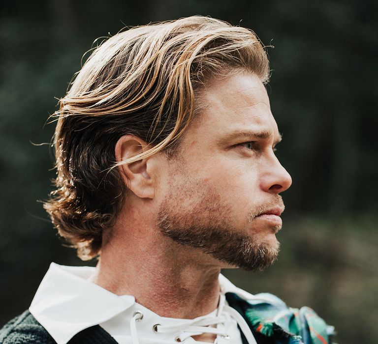 Bearded groom with long wavy hair in highland attire with aran tank top