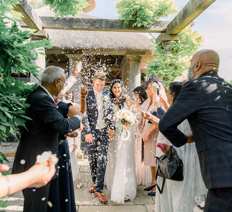 Bride & groom walk through wedding guests as they throw confetti around them