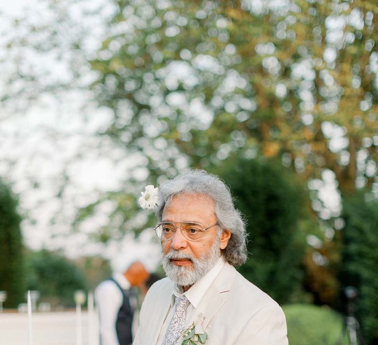 Wedding guest wears white suit outdoors during wedding reception