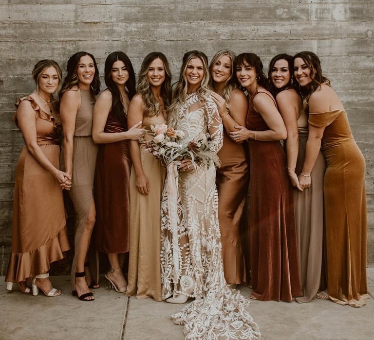 Bride stands with her bridesmaids who wear different styled gowns 