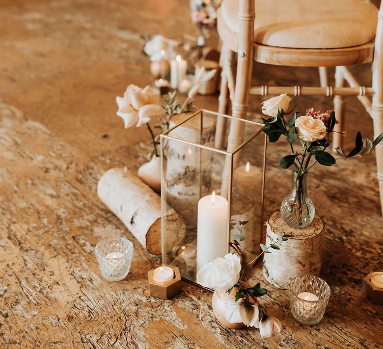 Pillar candles, pink roses and log aisle decor for wedding ceremony