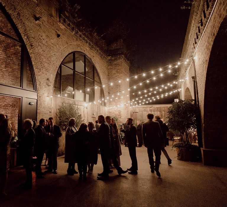 Wedding guests outside at city venue 100 Barrington, Brixton with fairy lights 