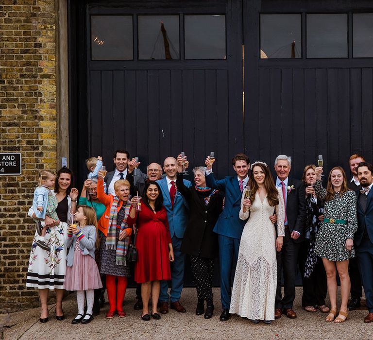 Wedding party in colourful and patterned outfits for wedding at Trinity Buoy Wharf in front of black doors 