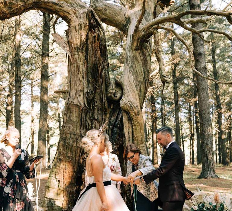 Outdoor wedding handfasting ceremony with bride in a blush tulle wedding dress 