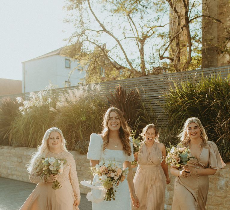 Bridesmaids in different style dresses in champagne gold colour with bride in puff sleeve wedding dress