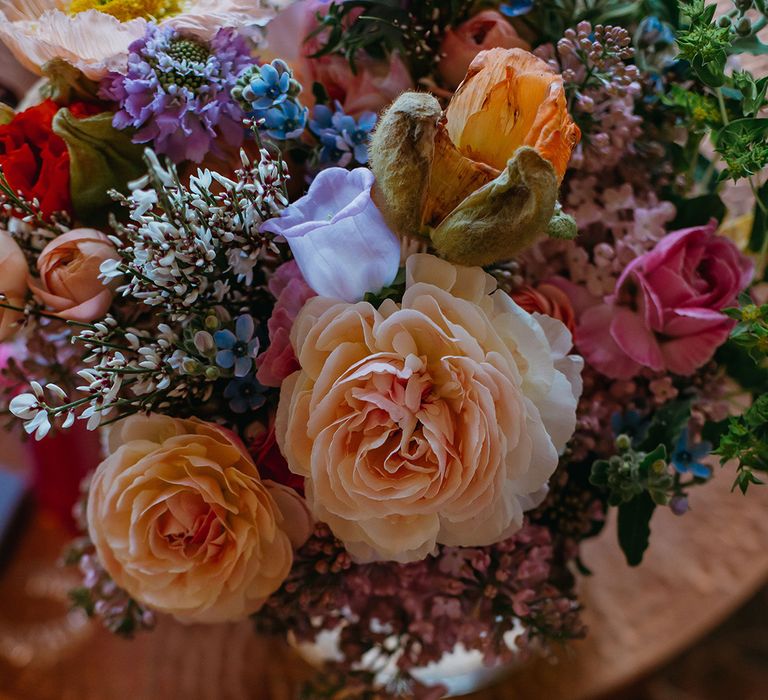 Pink, purple, blue, yellow, and orange wedding bouquet for spring wedding with waxflowers, bellflowers and roses 