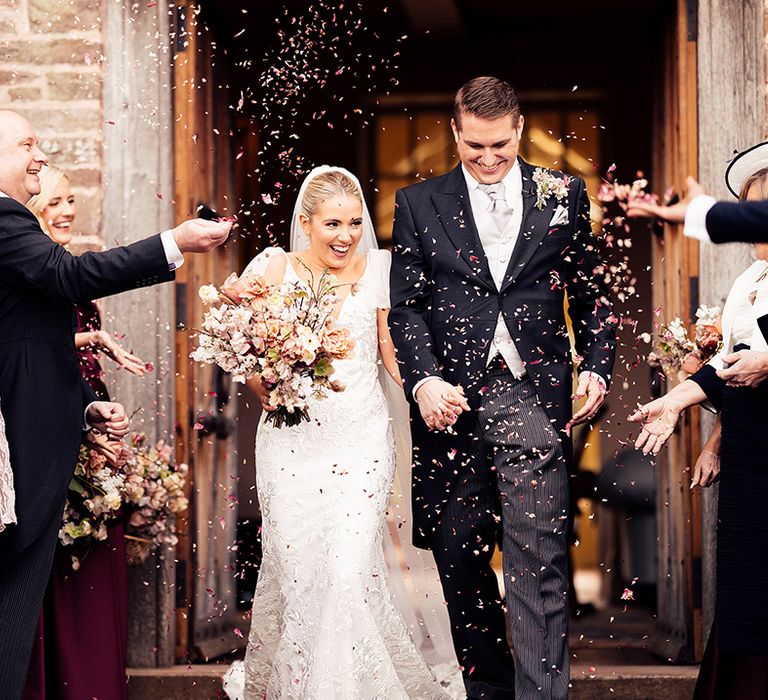 Wedding guests throw confetti over the bride and groom in celebration