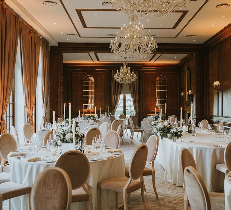 Wedding reception room at Hedsor House for classic wedding with chandeliers and circular wedding tables 