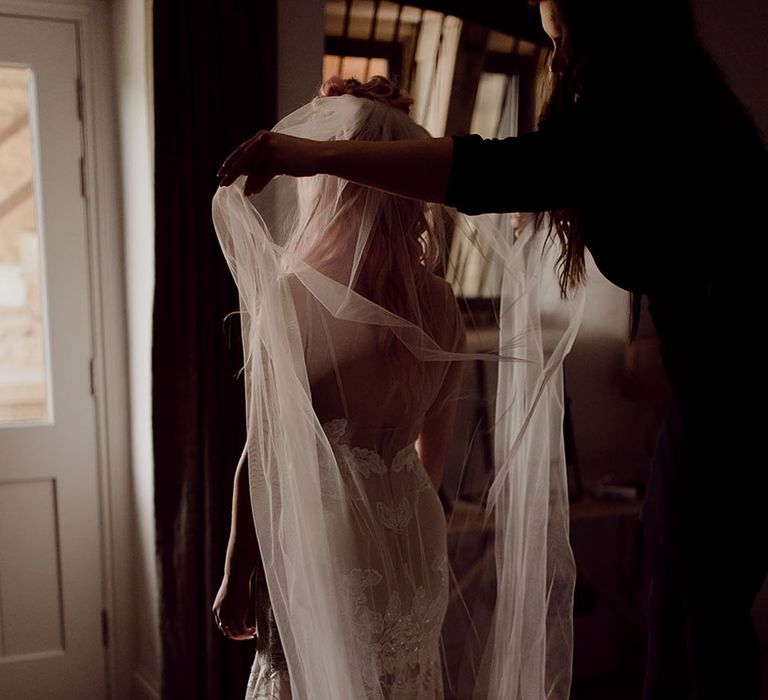 Bride wears dramatic cathedral floor-length veil in her hair with floral bridal crown 