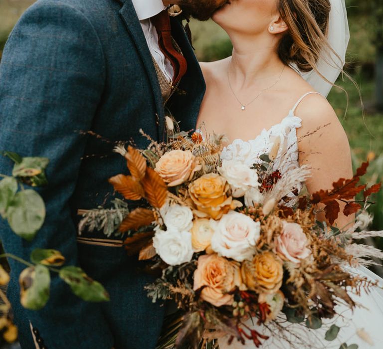 Bride and groom share a kiss with bride wearing a sequinned top and tulle skirt wedding dress and groom in a blue suit 