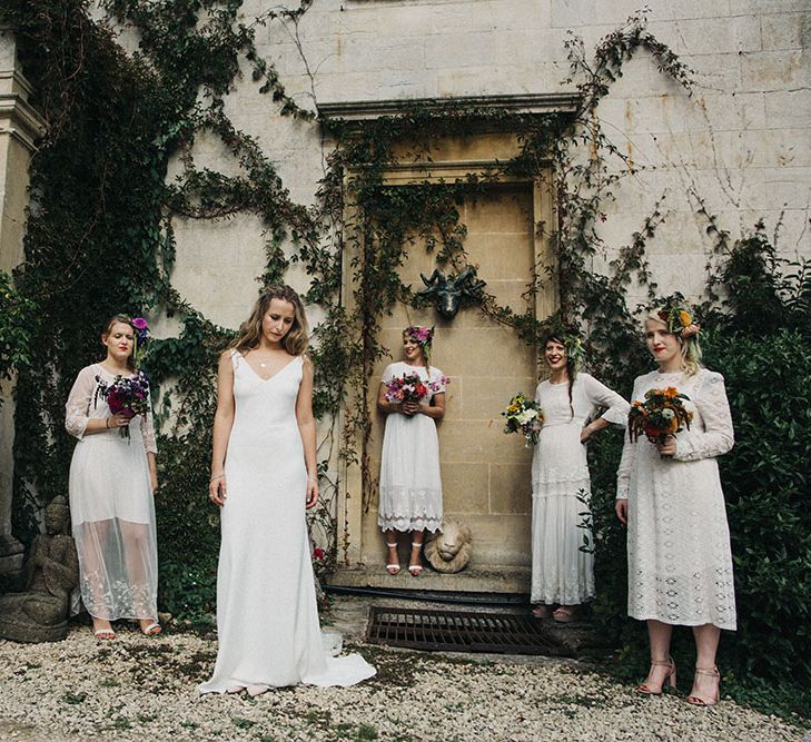 Bridal party wearing long lace white bridesmaid dresses and neutral coloured bouquets