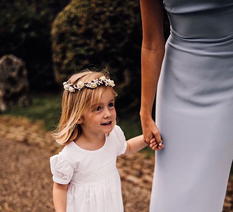 Flower girl in a white dress with a small pink bouquet with a flower crown