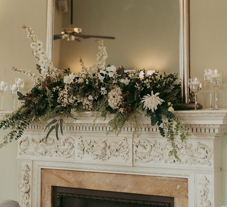 White faux wedding flowers on top of the fireplace in front of the mirror for classic country house wedding 