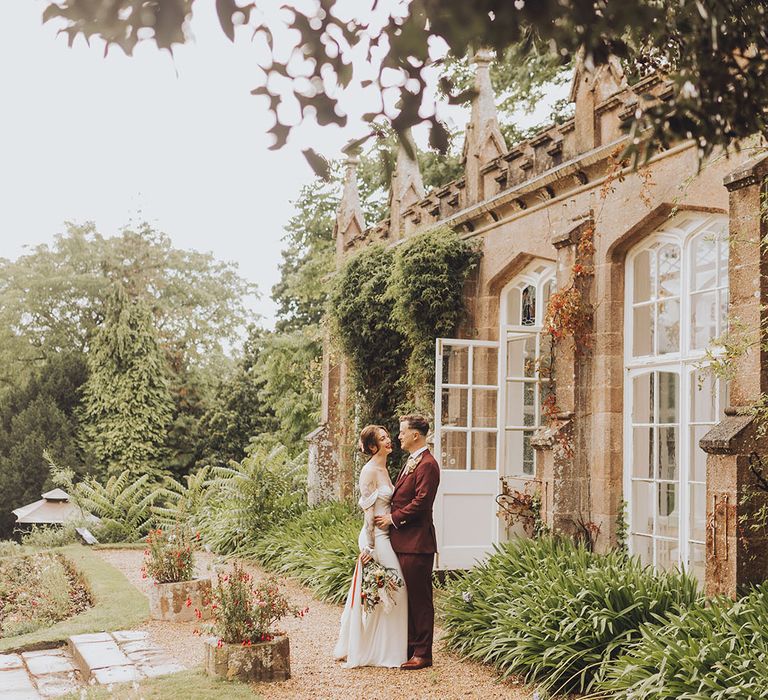 Bride & groom stand outdoors for couples portraits at St Audries Park wedding venue 