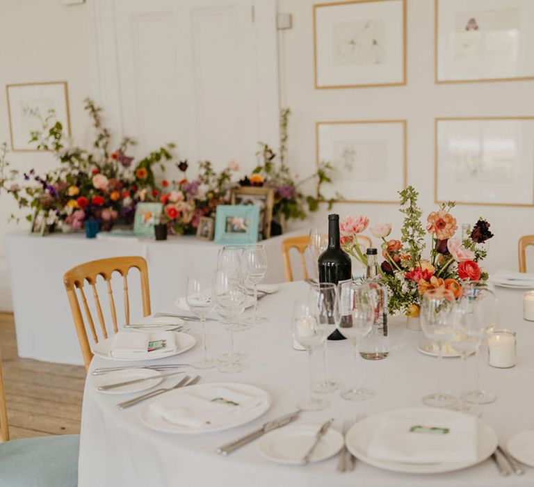 Bright floral centrepieces sit in the middle of round tables covered in white tablecloth complete with white candles 