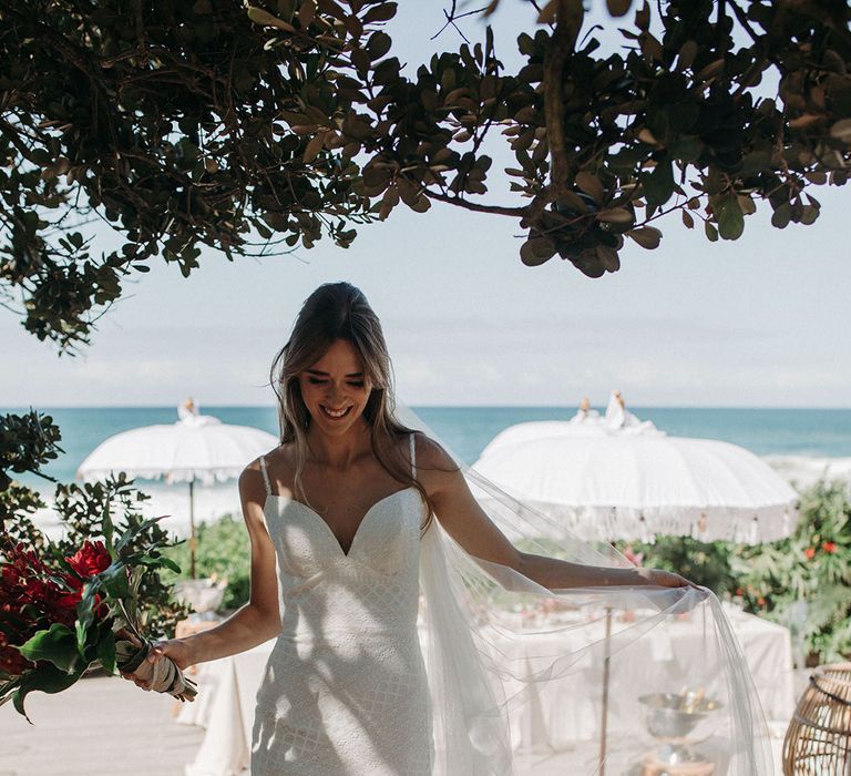 Destination beach wedding with the bride in a thin strap mermaid lace wedding dress 