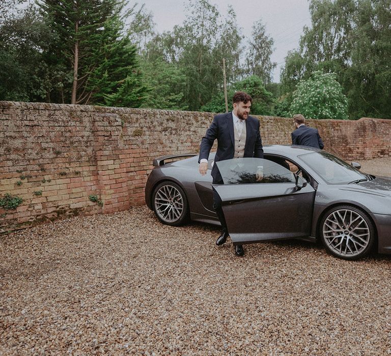 The groom and best man exit from the grey Audi R8 wedding car transport 