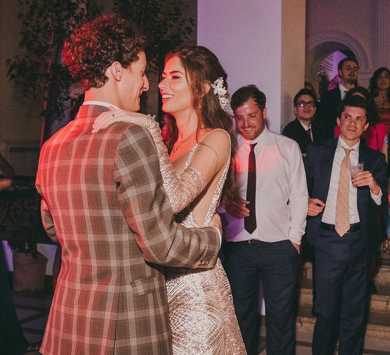 Bride and groom first dance with groom in a check suit and bride in a gold dress