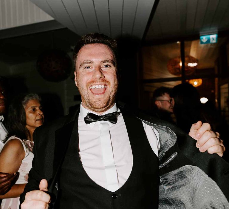 Groomsman wearing three piece black tuxedo suit with black bowtie at Tunnels Beaches wedding 