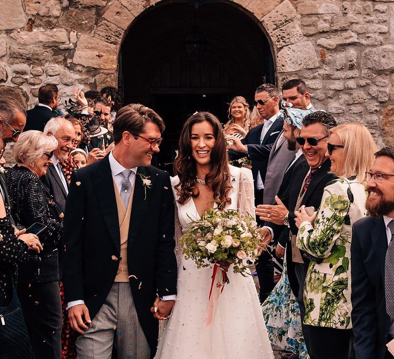 Bride and groom walk out of their ceremony to a classic confetti exit 