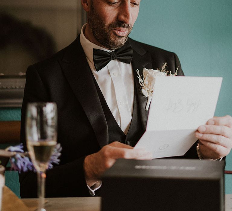 Groom sits reading a personal letter from the bride on the morning of the wedding 