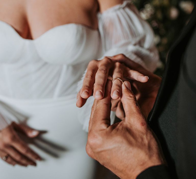 Groom places the ring on the bride's finger as part of the wedding ceremony 