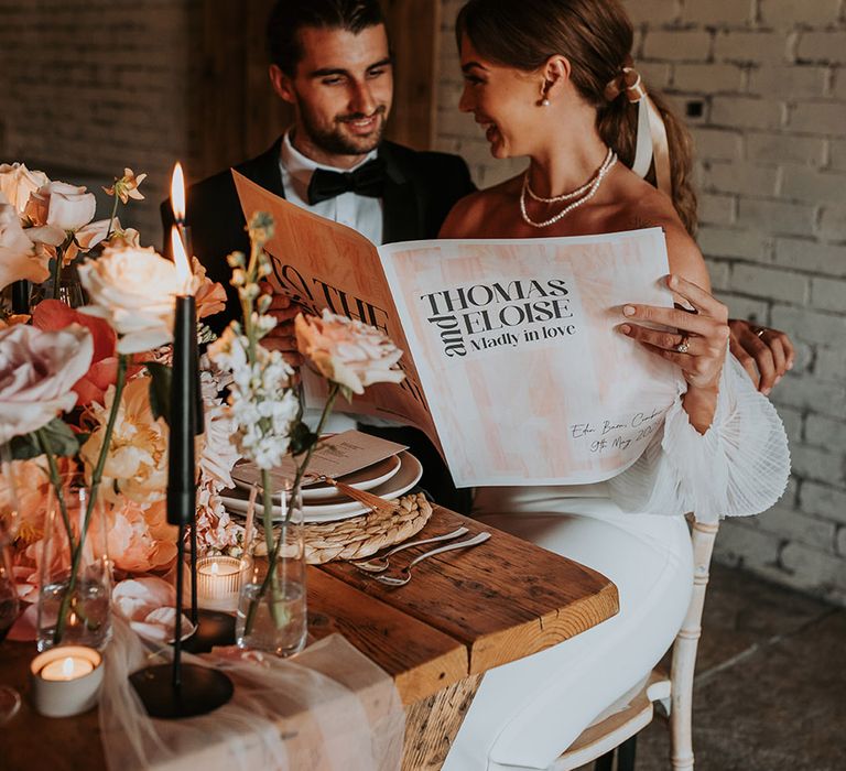 Bride and groom looking through pink, white and black wedding newspaper stationery 