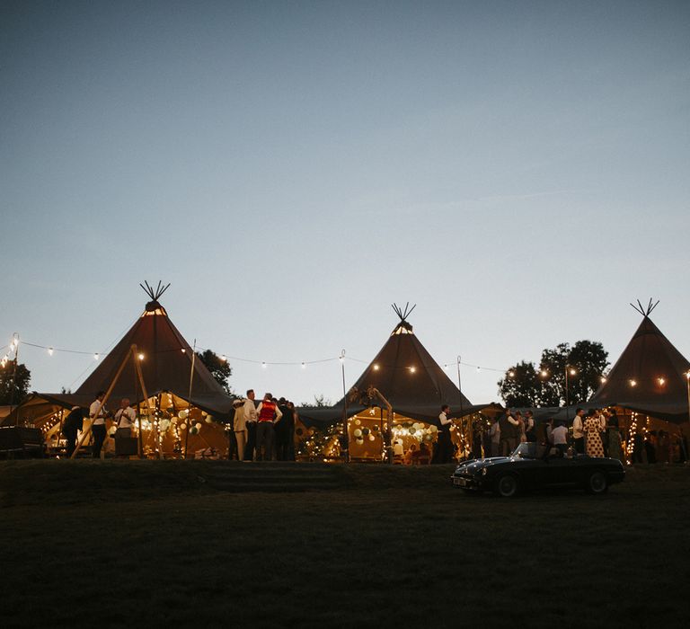 Wedding tipi lit up with gold fairy lights at dusk