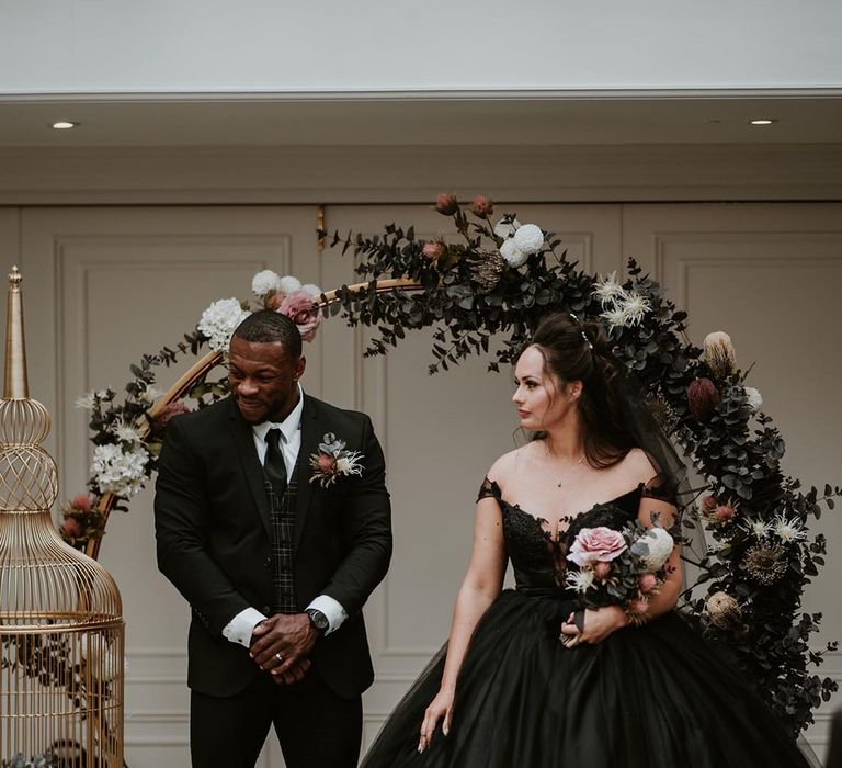 Bride in black wedding dress with strapless style in front of moongate