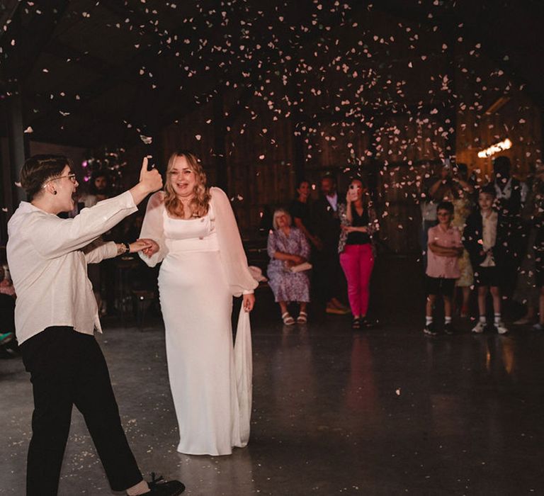 The two brides share their first dance together as confetti explodes around them