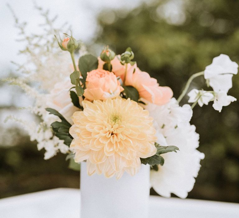 White vase full of wedding flowers in peach tones 