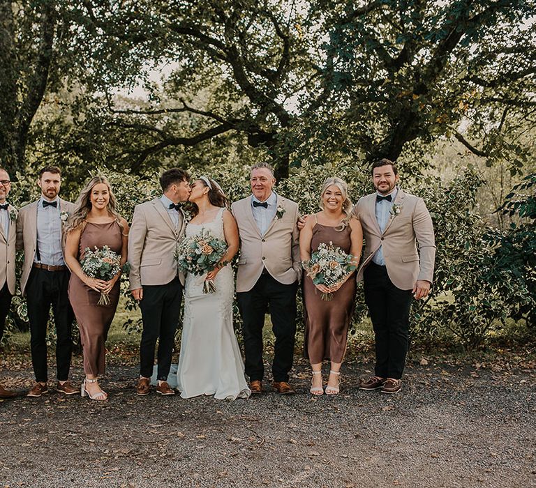 Bridal party wearing brown bridesmaid dresses with groomsmen in beige suits for wedding party 